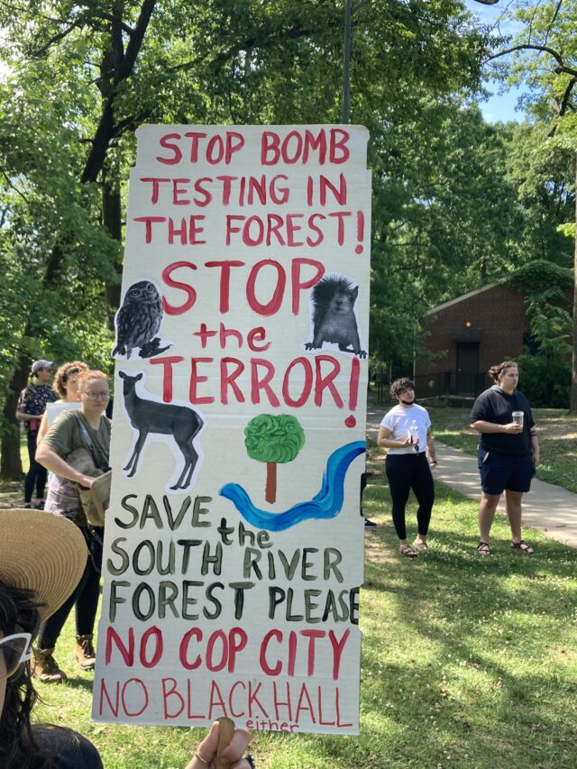 A protest sign that reads: “Stop Bomb Testing In The Forest! STOP the TERROR! Save the South River Forect Please. NO COP CITY. No Black Hall either.” 